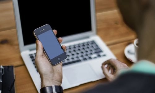 picture of a man about to update a client via SMS on his mobile phone