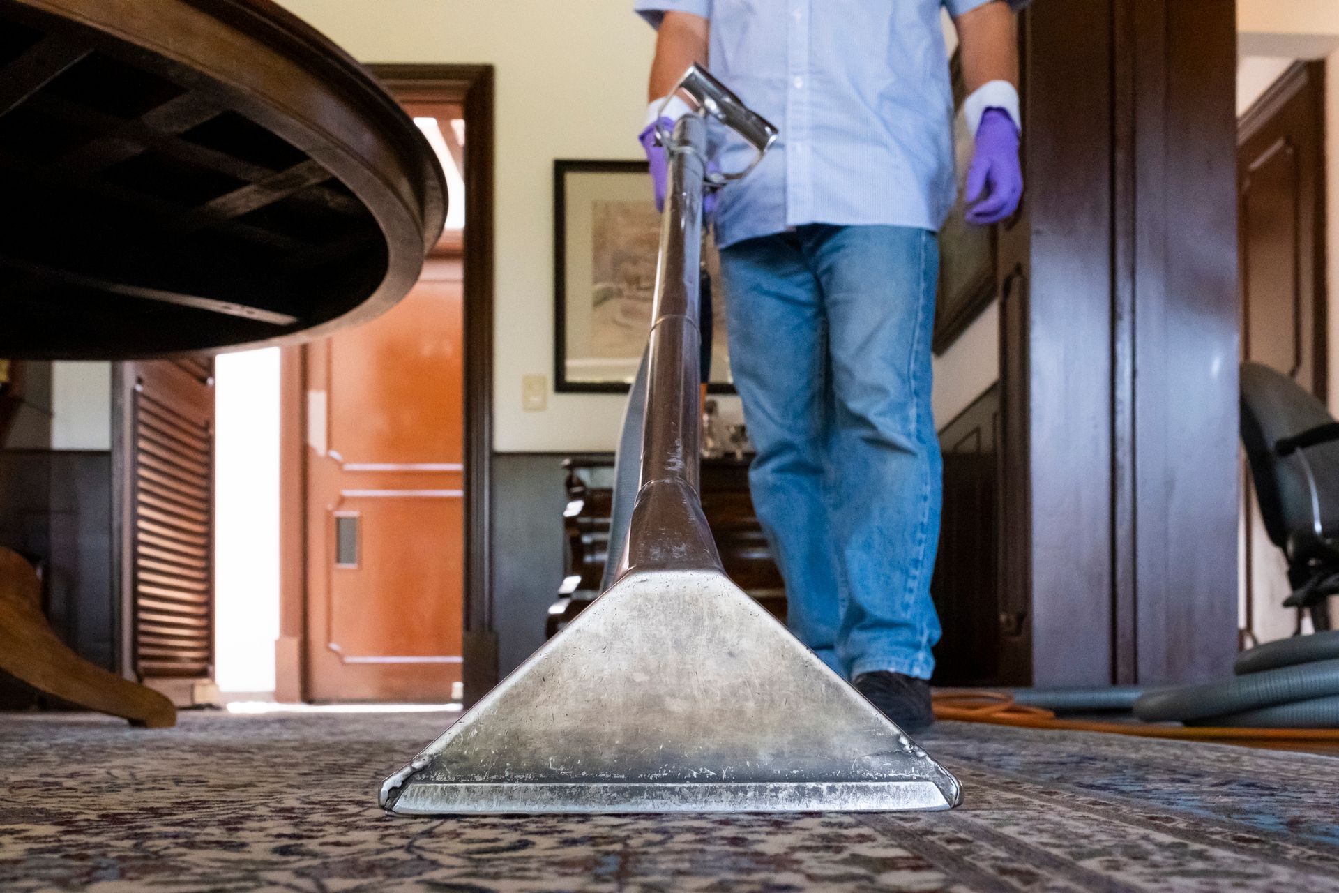 A man is cleaning a carpet with a vacuum.