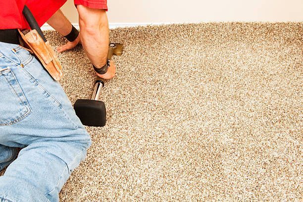 A professional using a knee kicker to stretch a bedroom carpet.