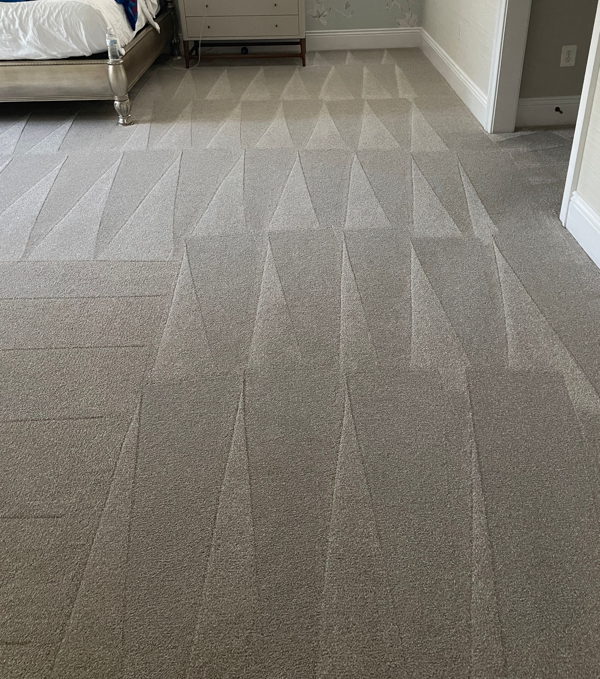 Gray carpet with a patterned design in a bedroom with furniture.