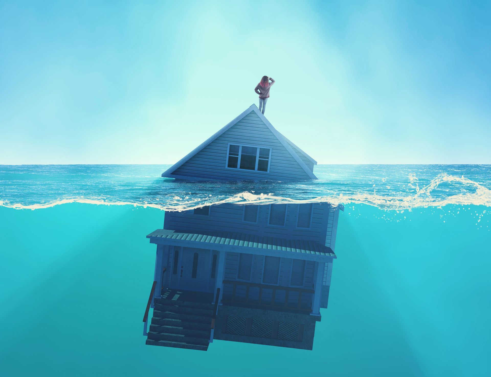 Flooded house floating in blue water with a person standing on the roof