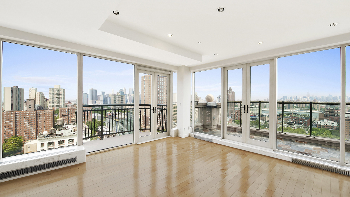 Real estate agent shaking hands with a smiling couple in a bright room.