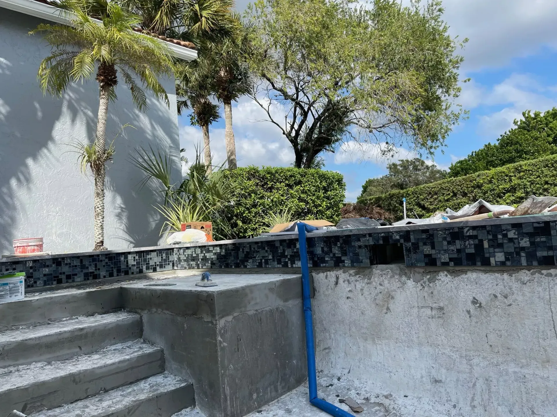 A swimming pool is being built in the backyard of a house.