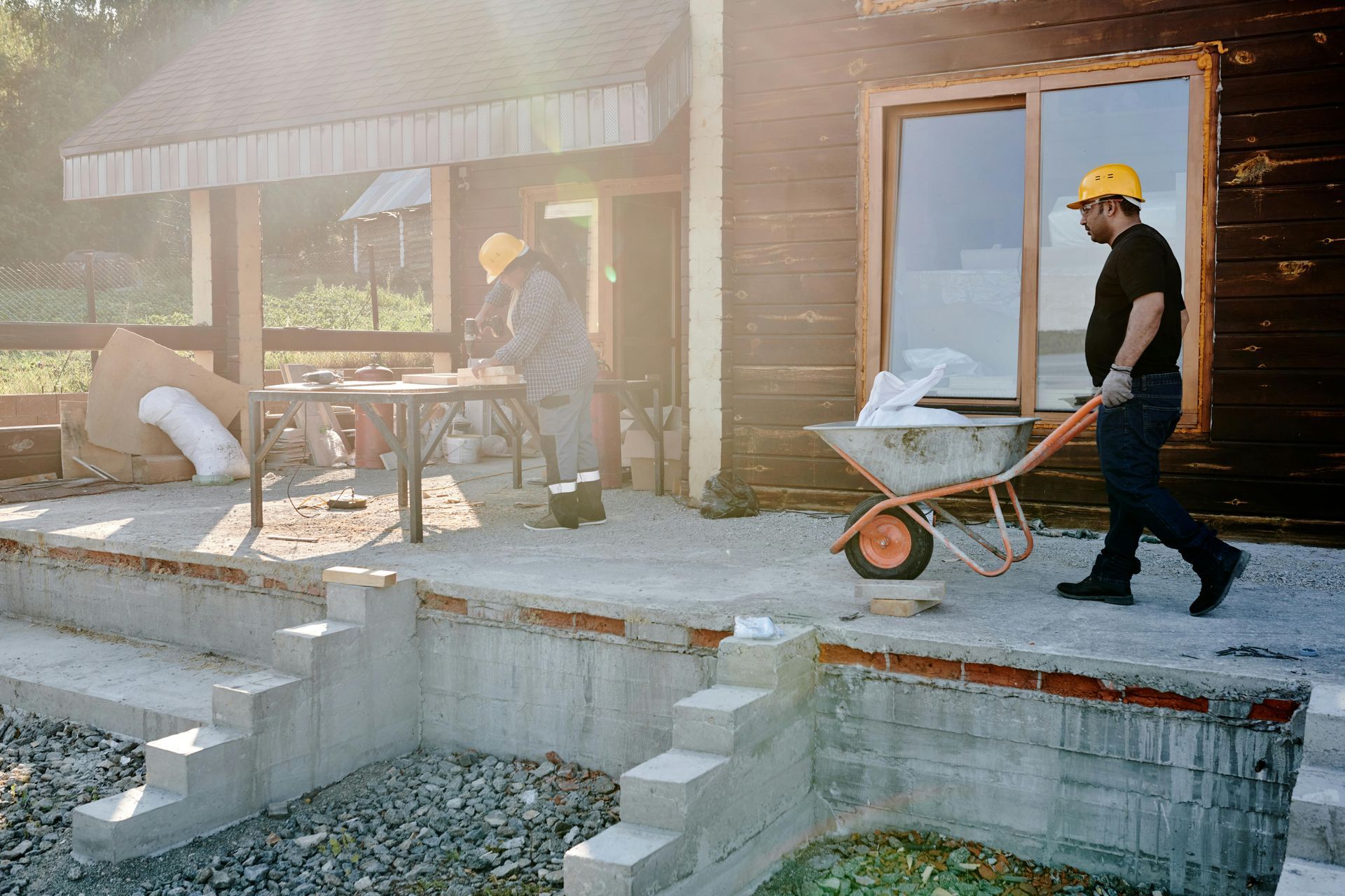 A large brick house is being built in the middle of a dirt field.