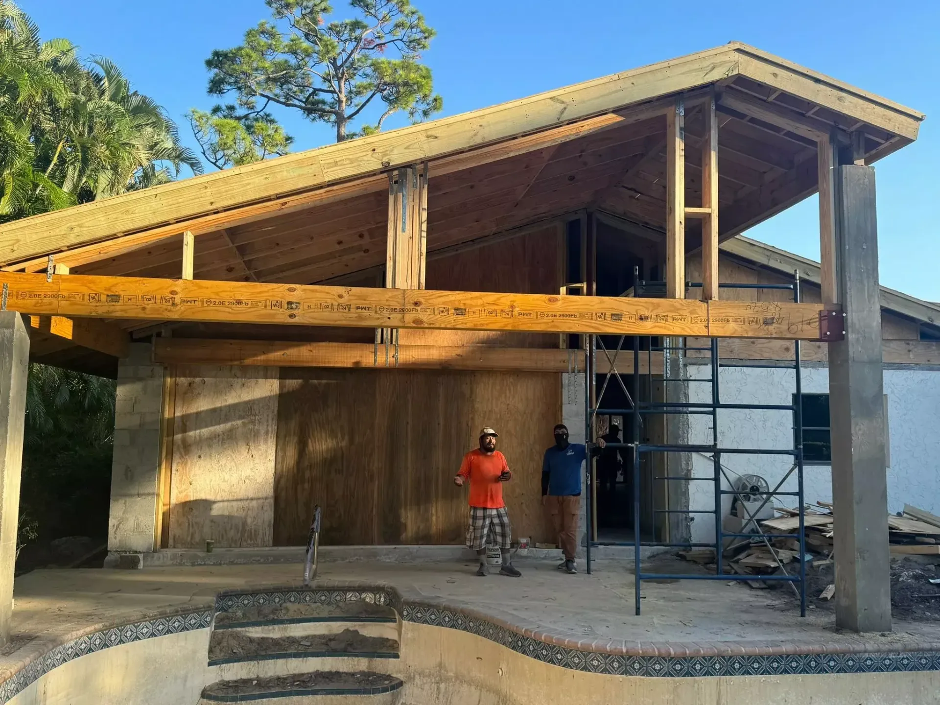 Two men are standing in front of a house under construction