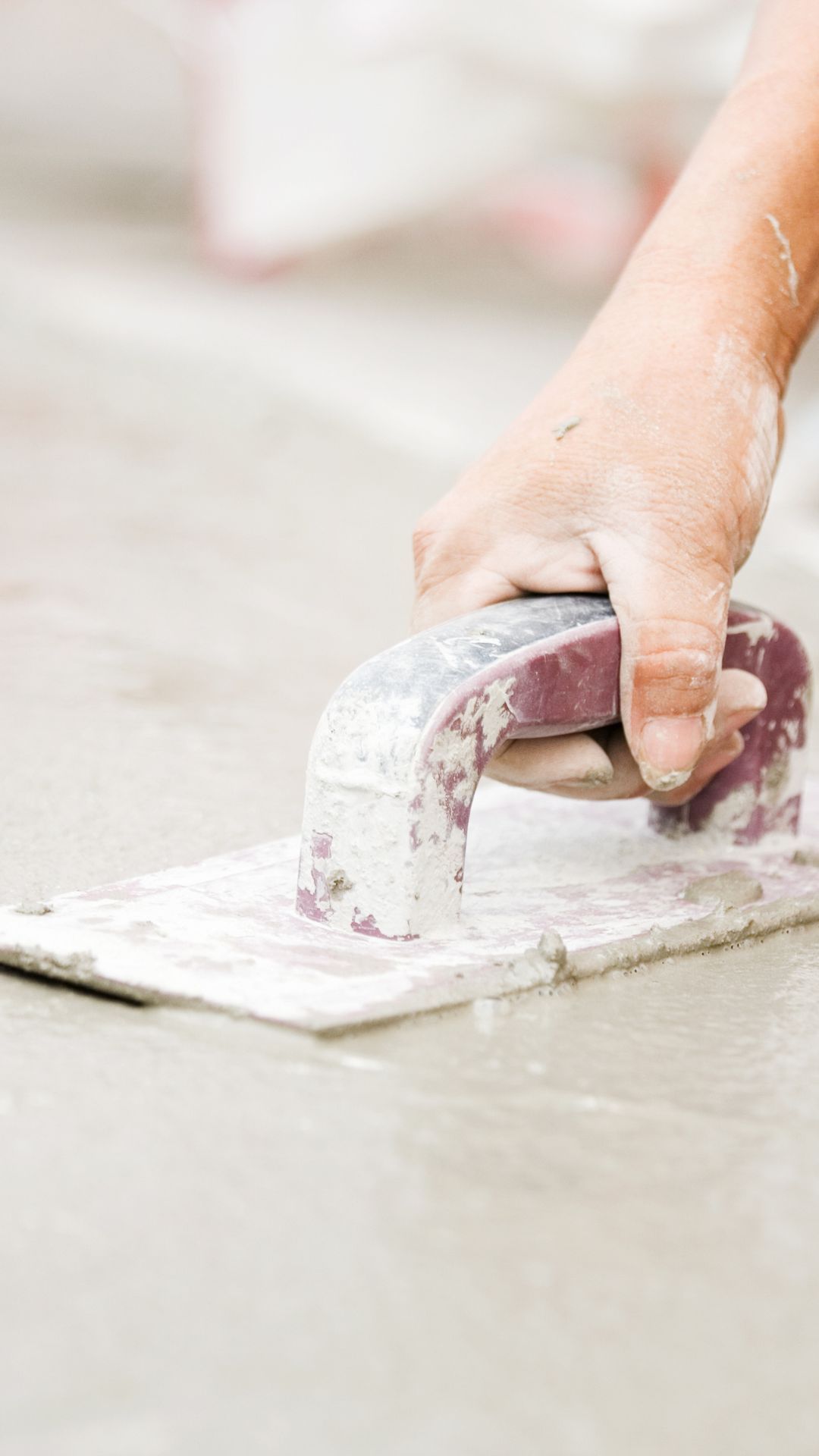 A person is plastering a tile floor with a trowel.
