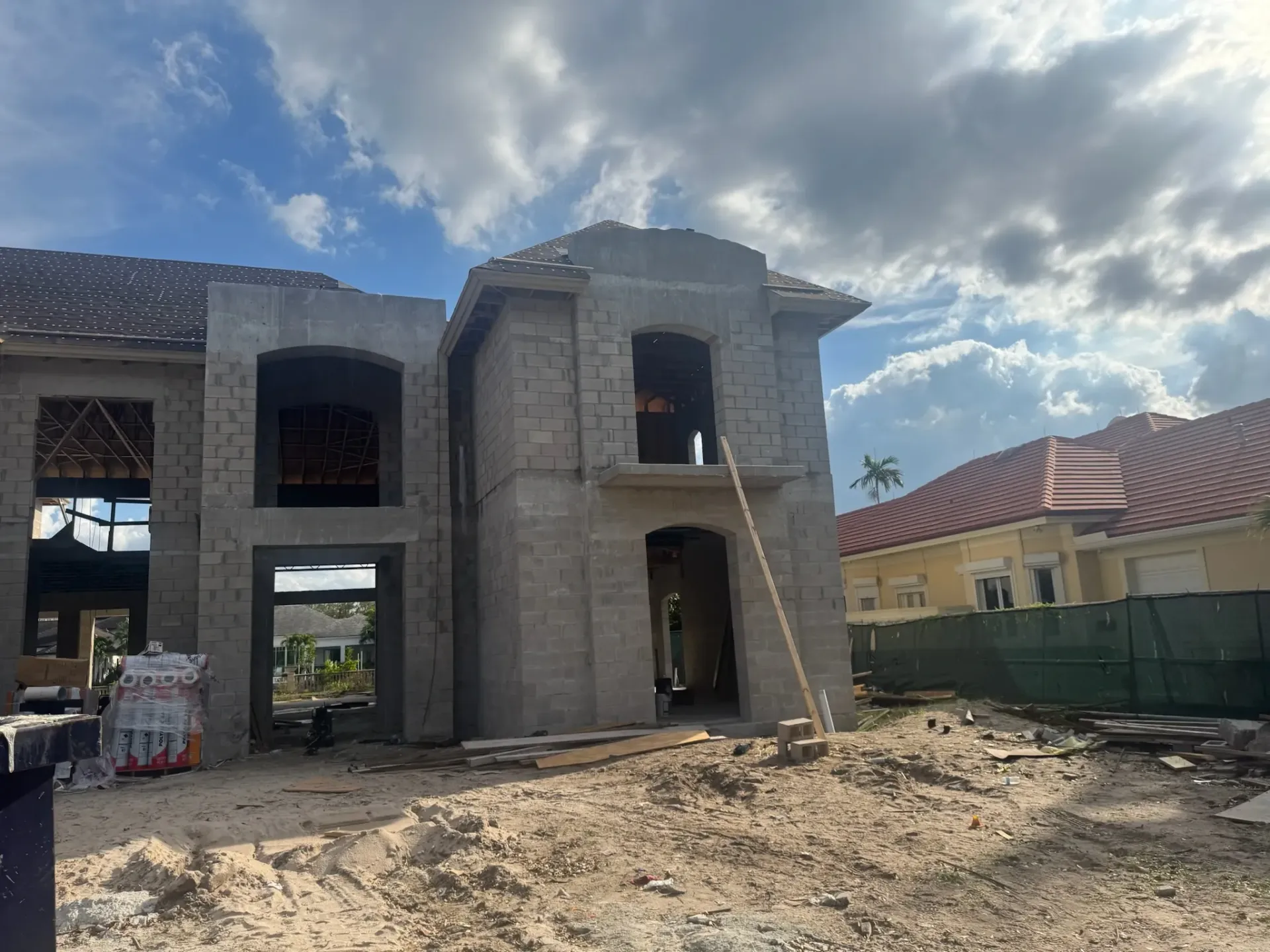 A large brick house is being built in the middle of a dirt field.