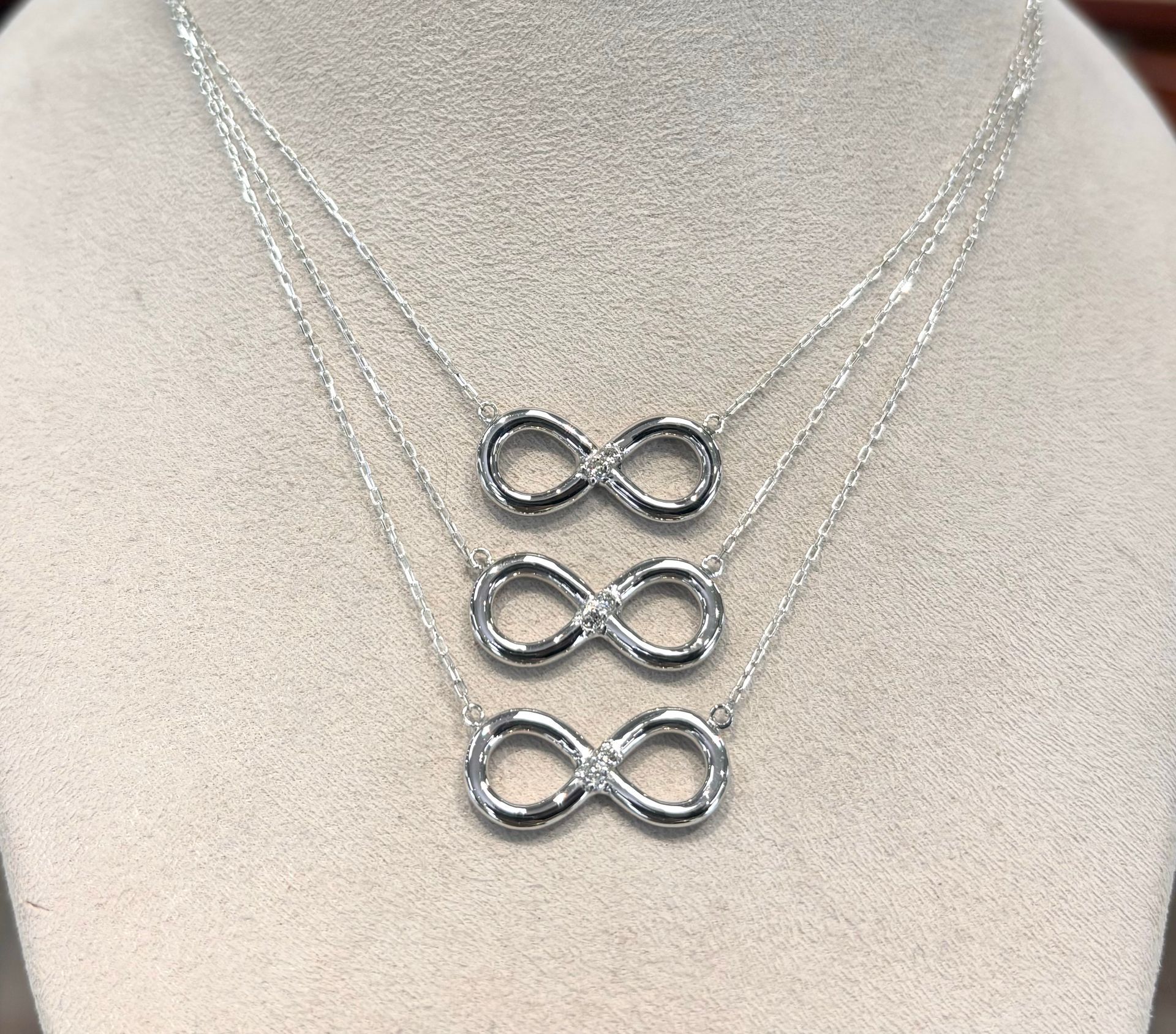 Three necklaces with infinity symbols on them are on a mannequin