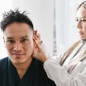 Woman touching a man’s ear during a grooming or medical check in a bright room