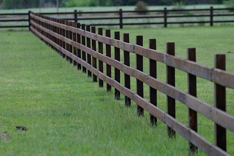 A Long Wooden Fence Surrounds a Grassy Field — Osborne Fencing in Robertson, NSW