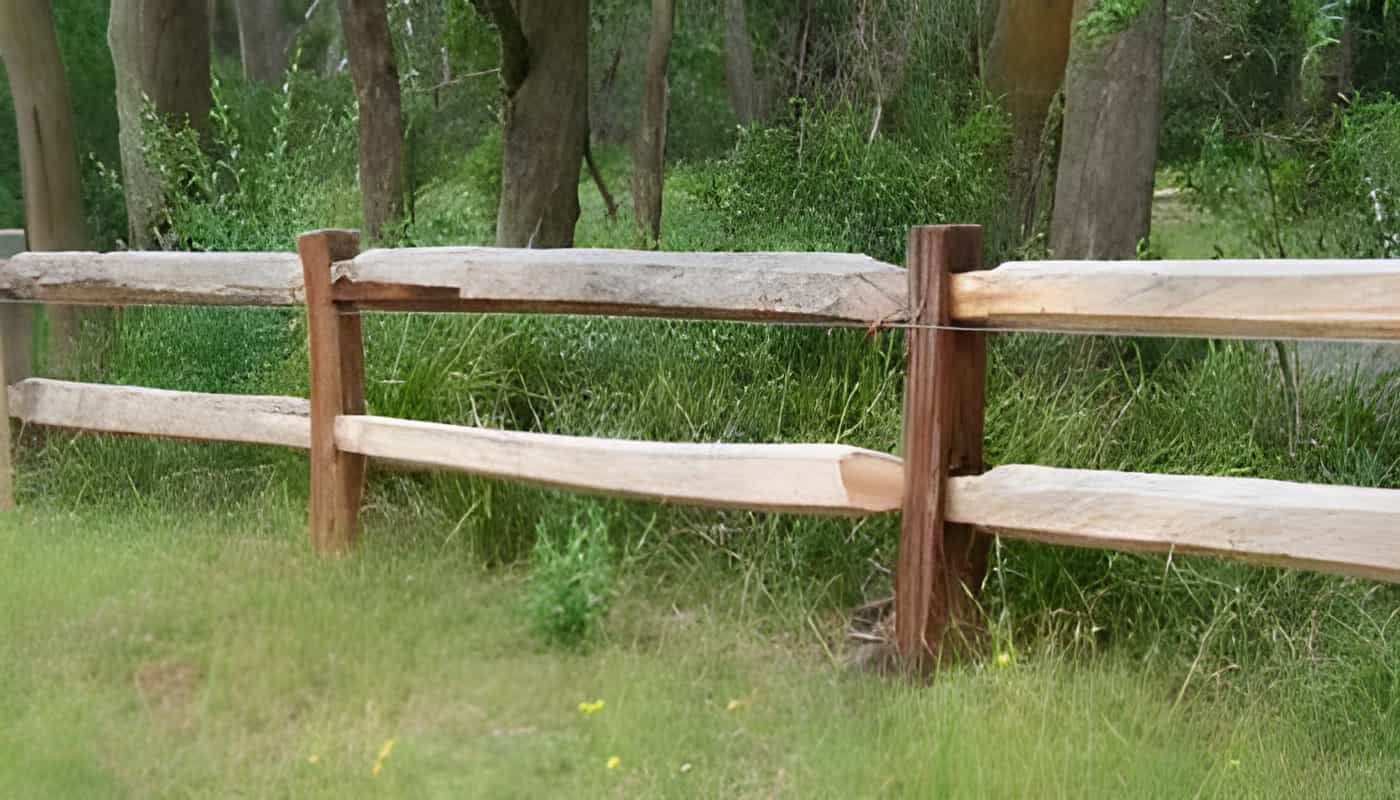 A Wooden Fence is in the Middle of a Grassy Field — Osborne Fencing in Moss Vale, NSW