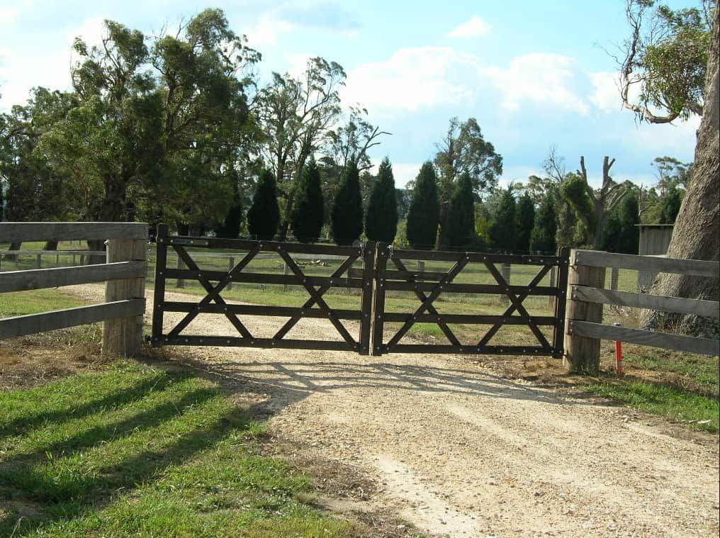 A Dirt Road With a Wooden Fence and a Gate — Osborne Fencing in Burradoo, NSW