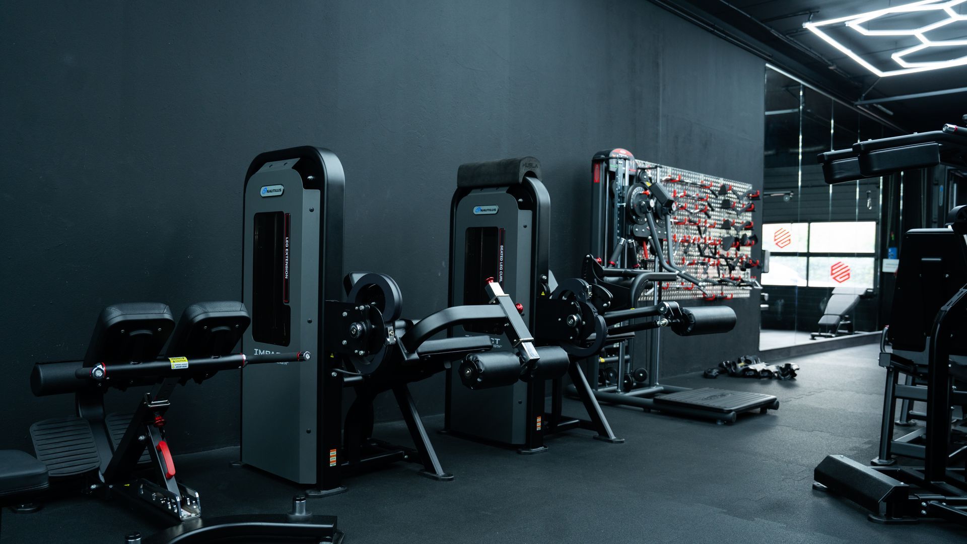 Interieur van een sportschool met gewichtsapparaten in een donkere, moderne ruimte.