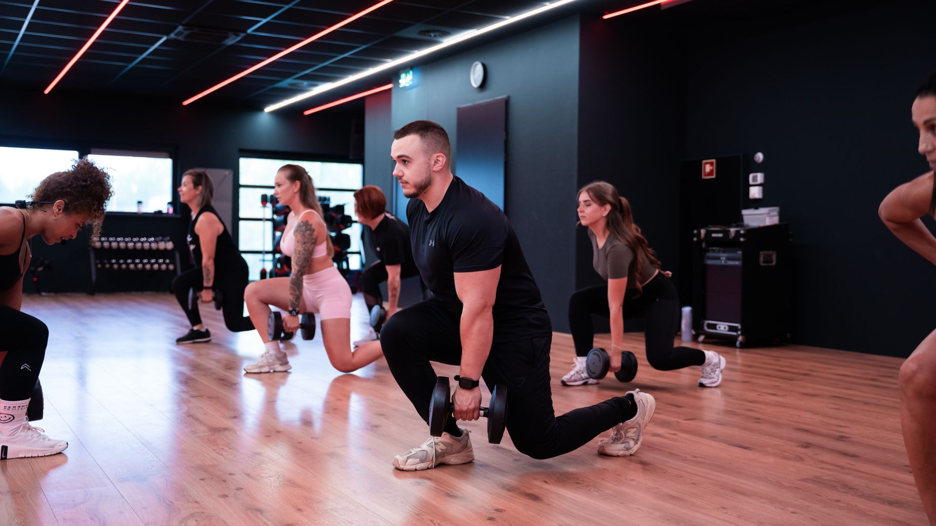 Groepstraining met dumbbells in een sportschool. Mensen doen lunges.