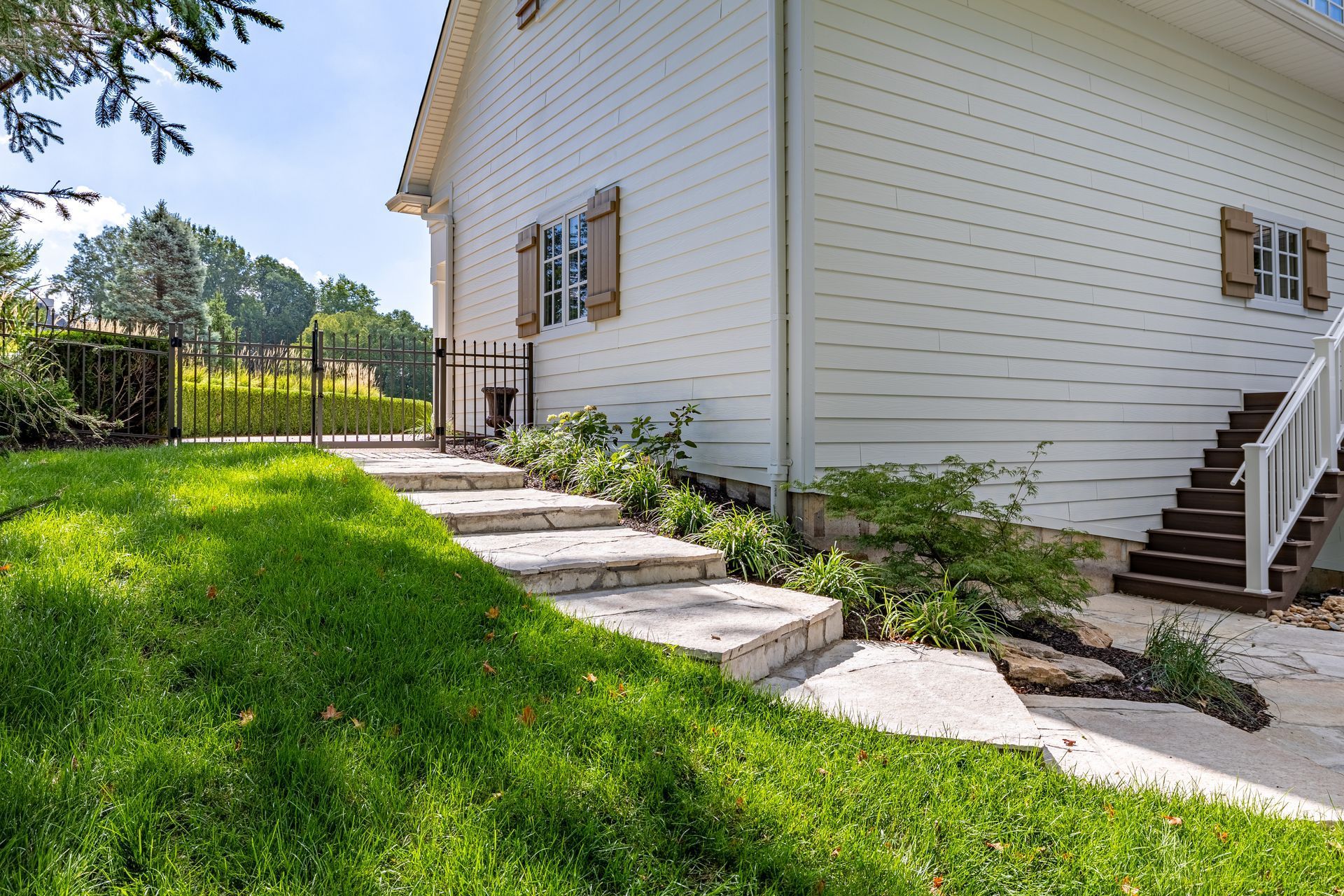 White house exterior with stone walkway, green lawn, and stairs on the right