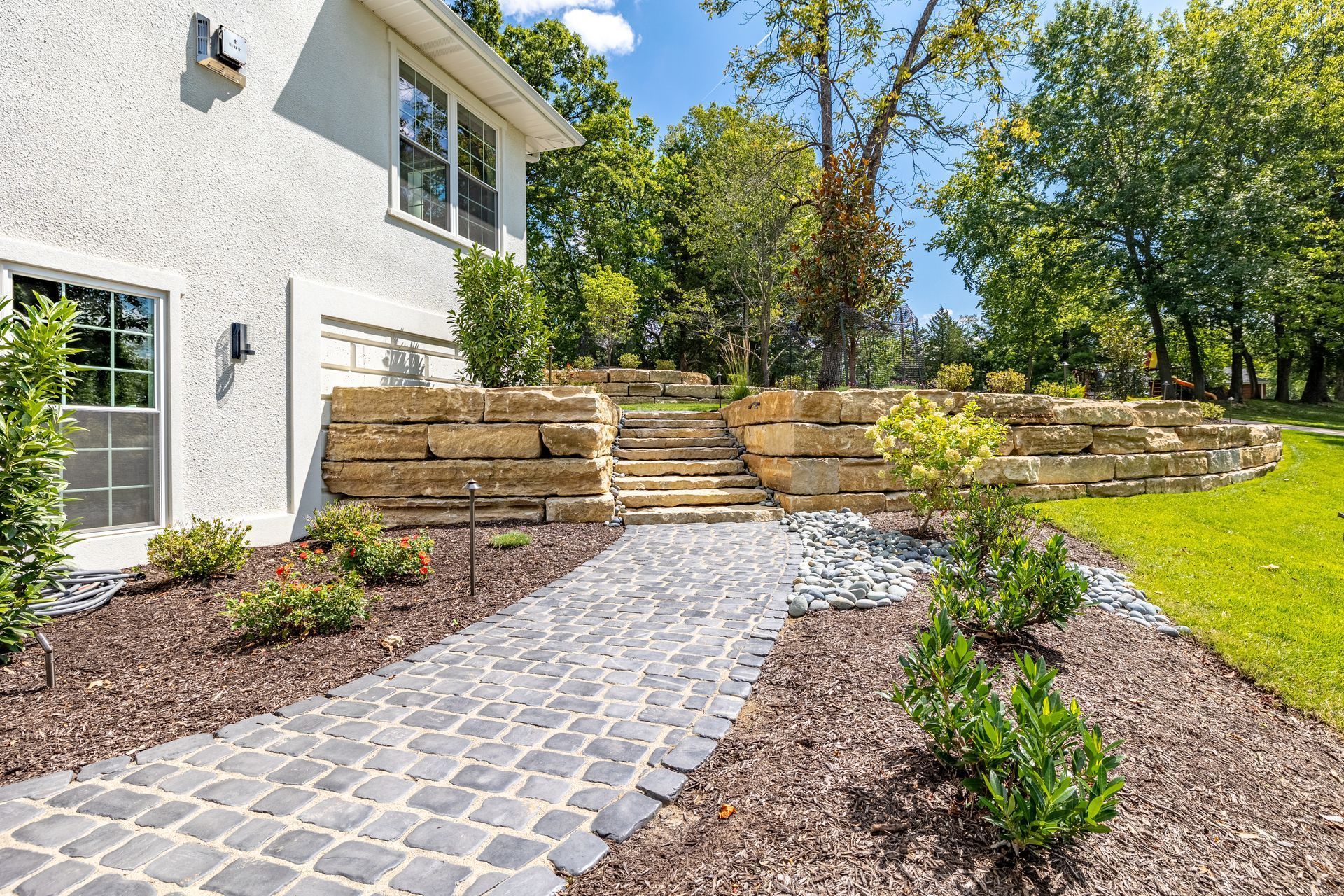 There is a stone walkway leading to the front of the house.