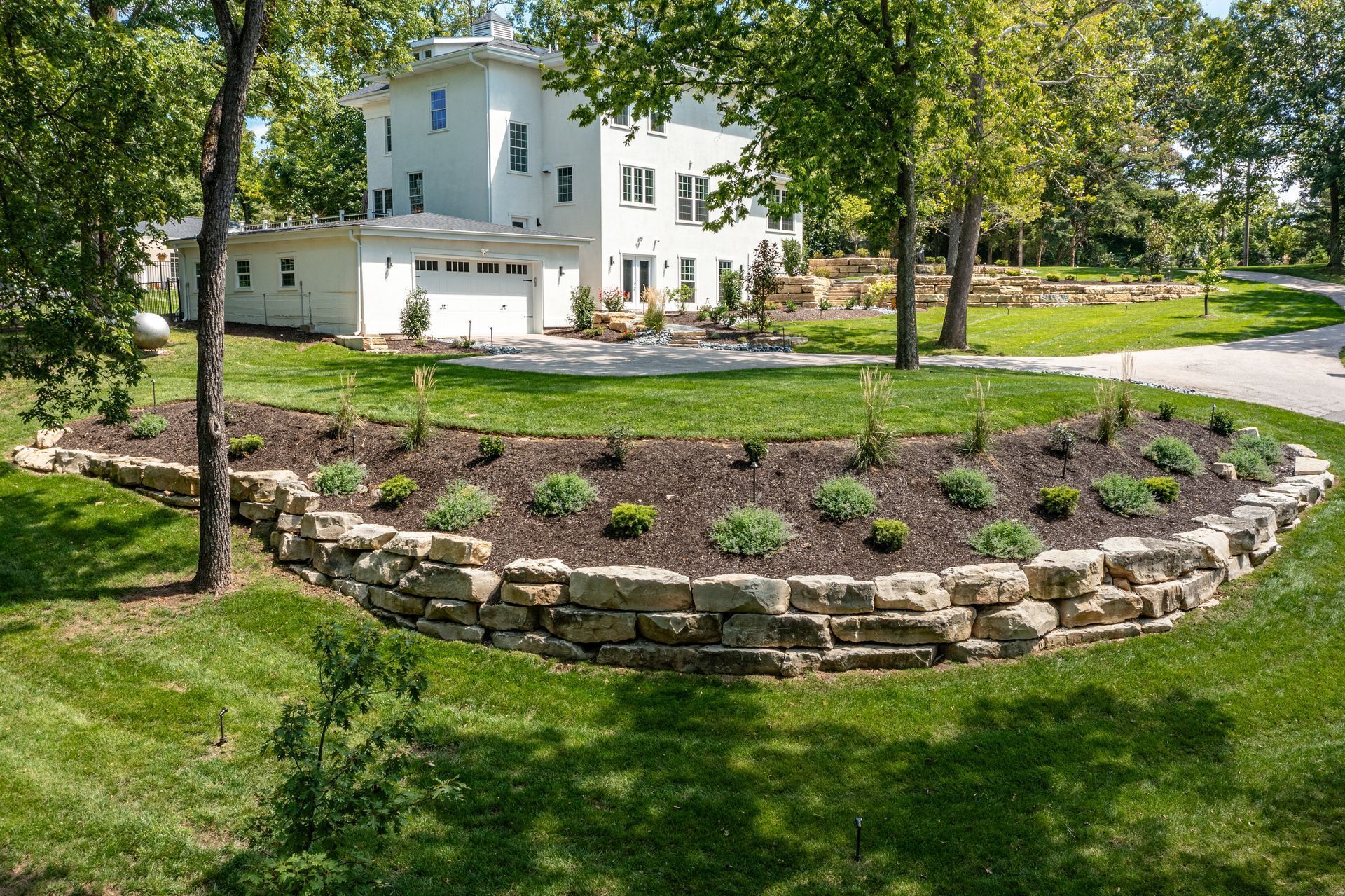 A large white house with a stone wall in front of it.