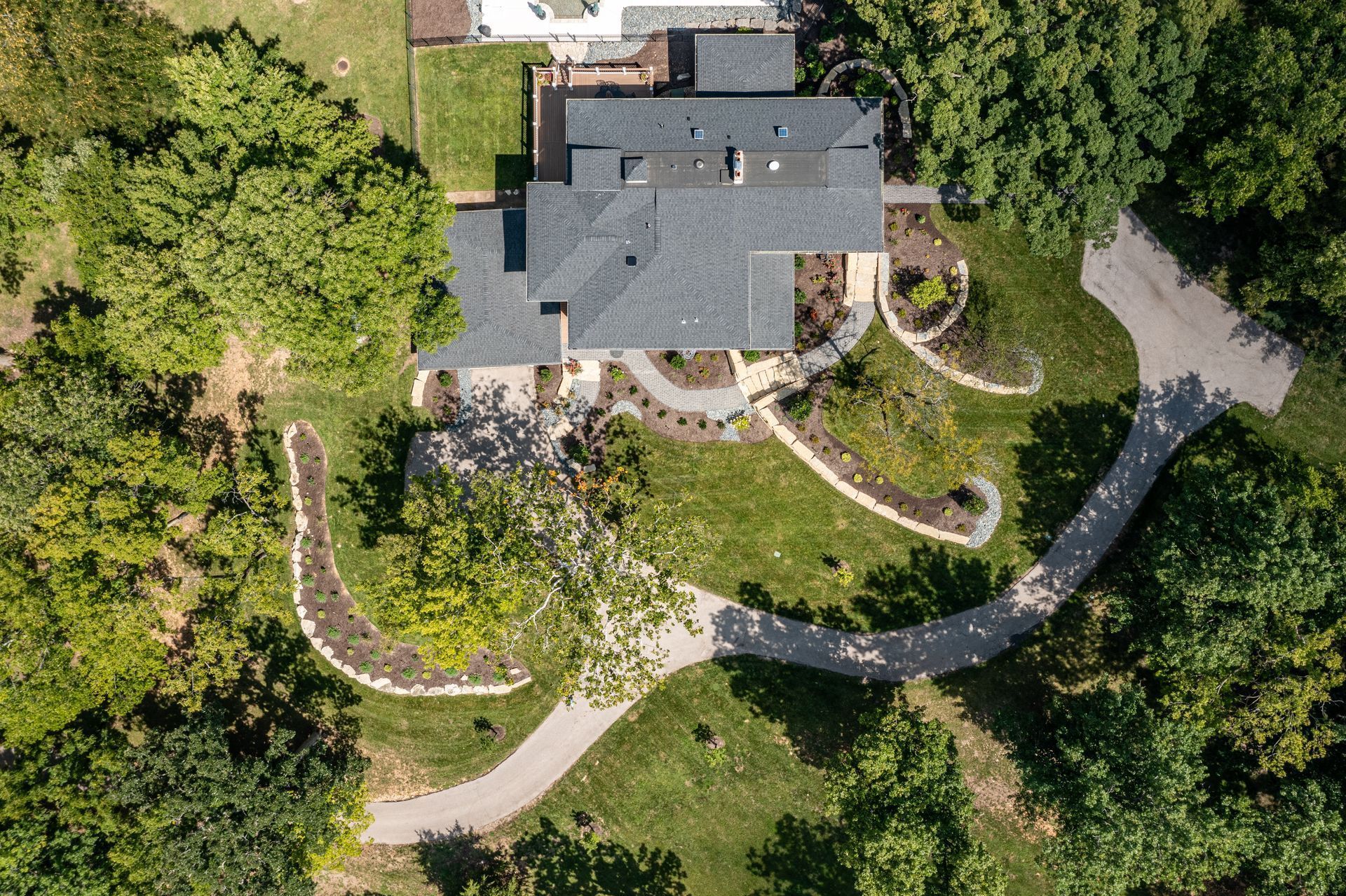 An aerial view of a large house surrounded by trees and grass.