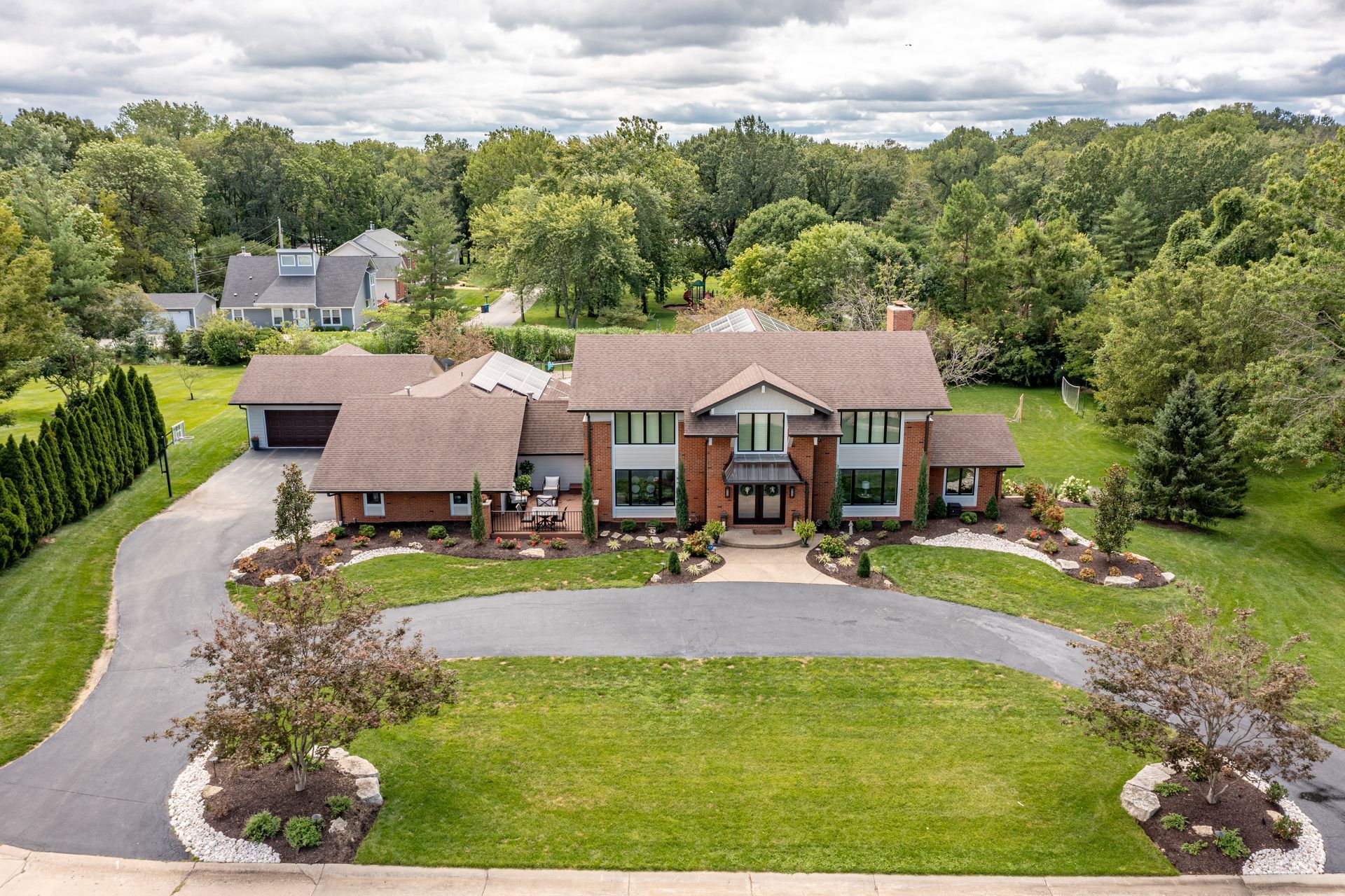 An aerial view of a large house surrounded by trees and grass.