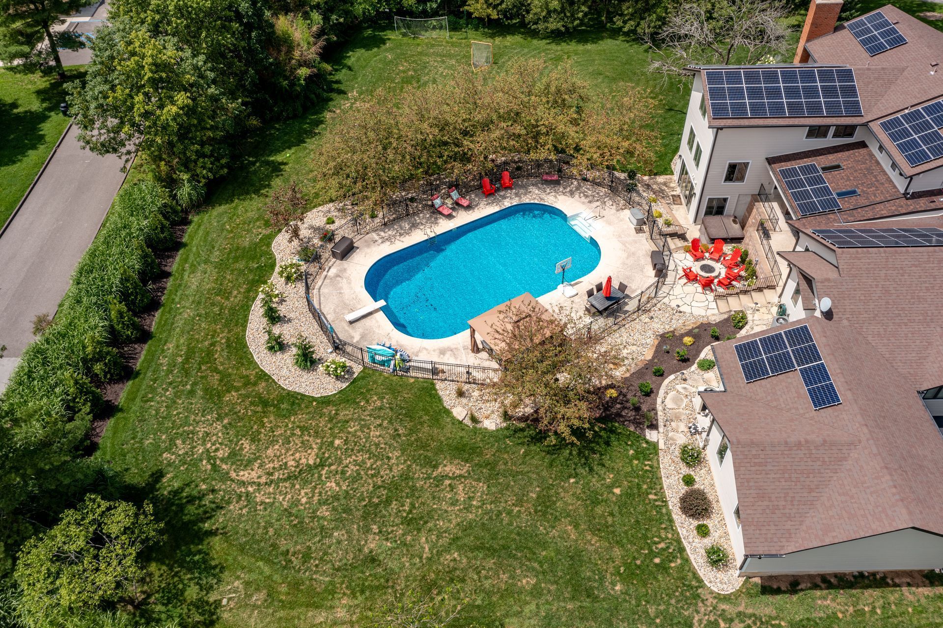 An aerial view of a house with a swimming pool and solar panels on the roof.