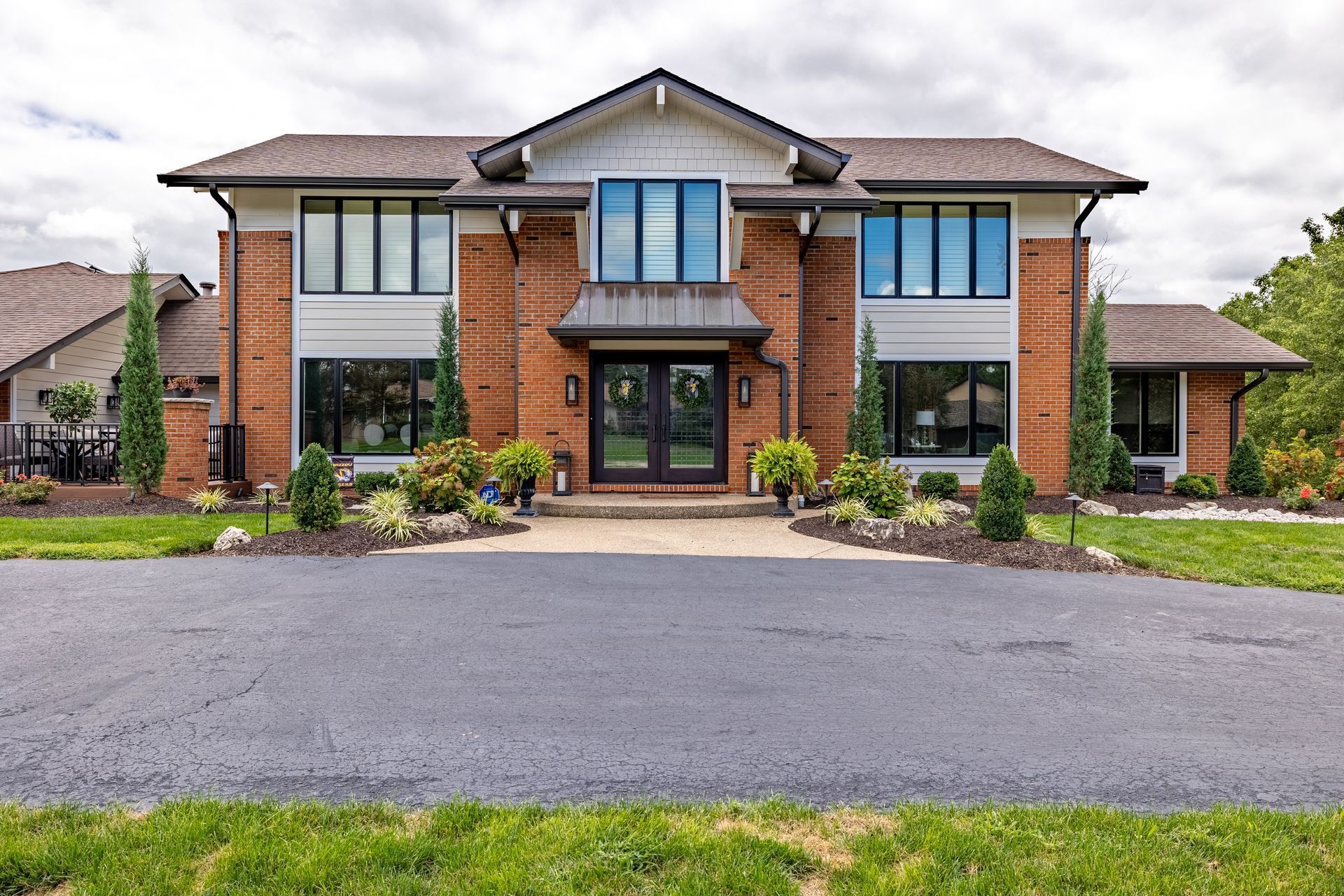 A large brick house with a lot of windows is sitting on top of a lush green field.