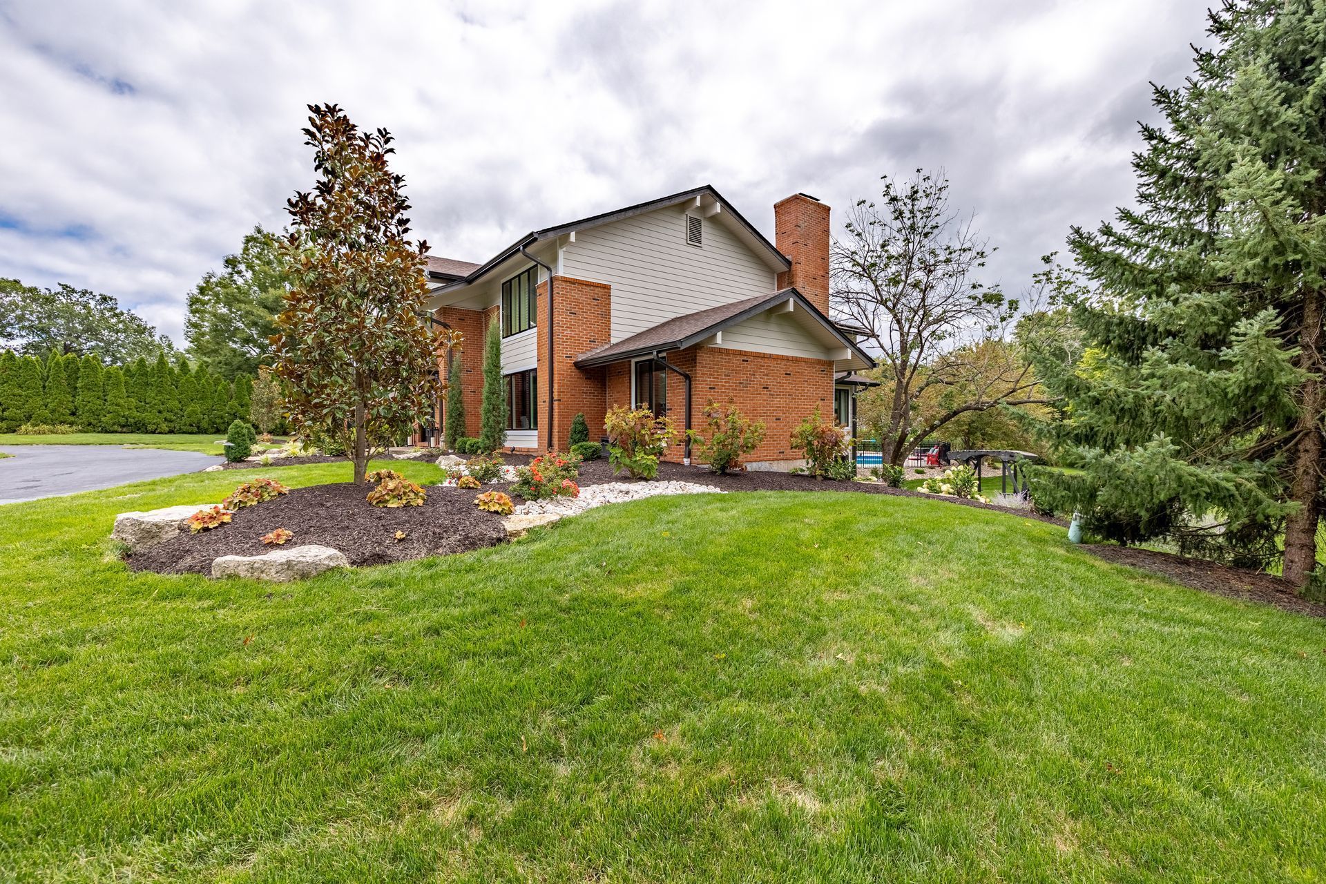 A large brick house with a large lawn in front of it.