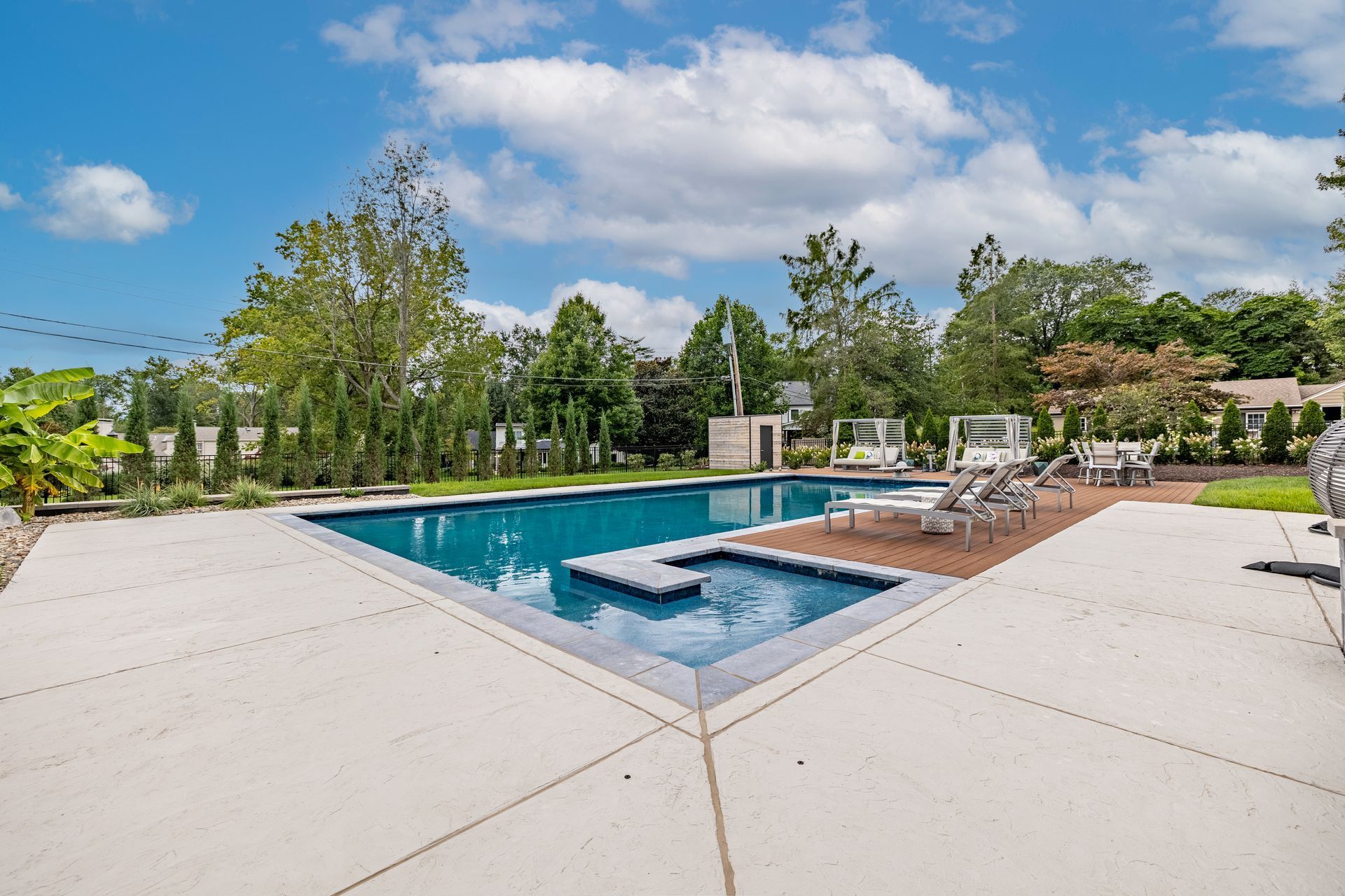 There is a large swimming pool in the middle of the backyard.