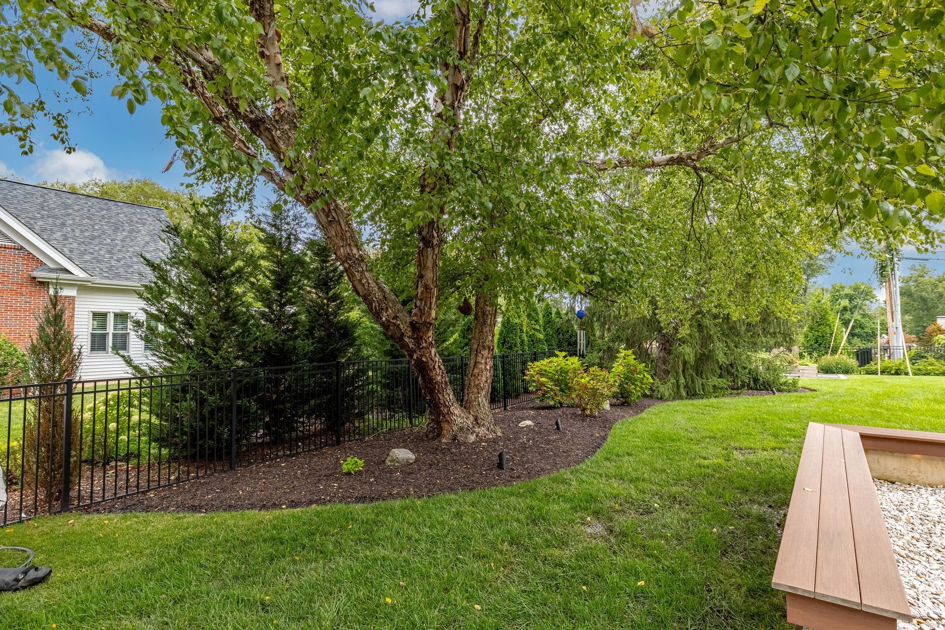 There is a wooden bench in the backyard of a house.