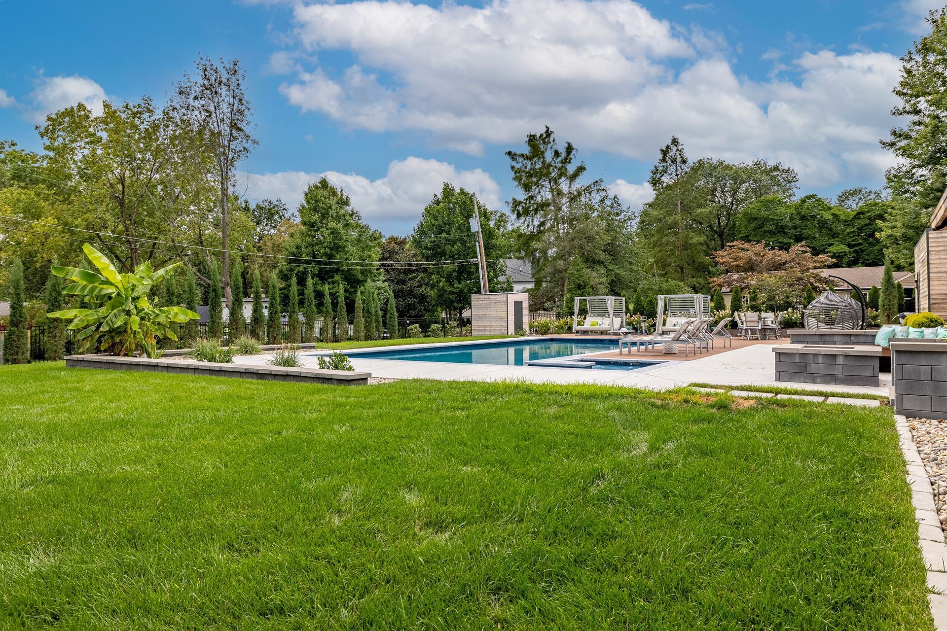 There is a large swimming pool in the backyard of a house.