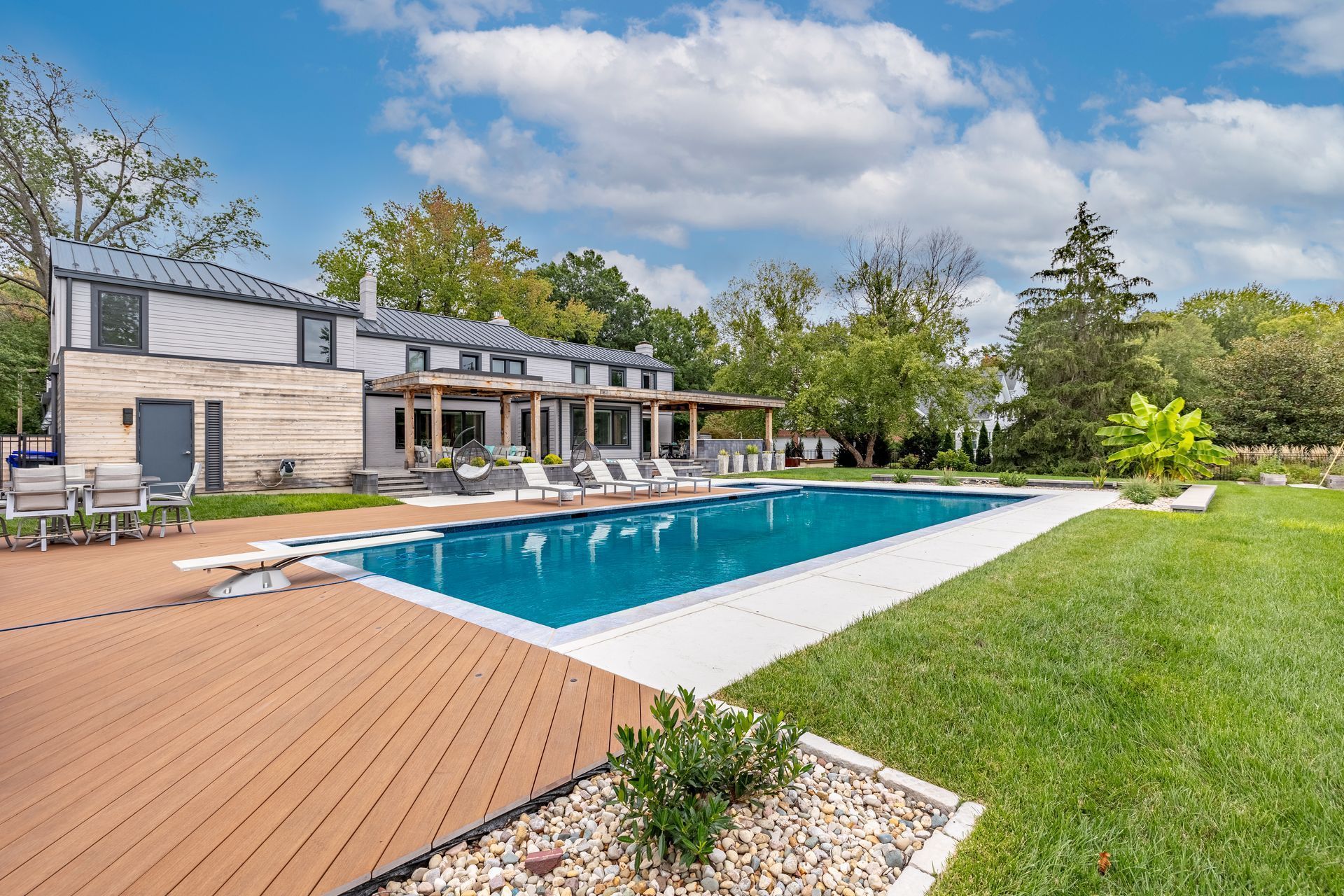 There is a large swimming pool in the backyard of a house.