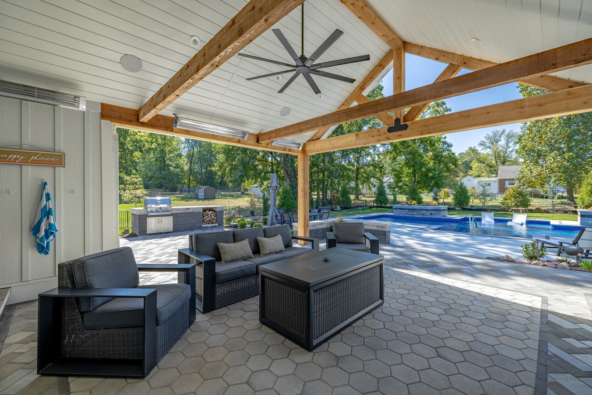 Covered patio with wicker seating, ceiling fan, and poolside view of a backyard