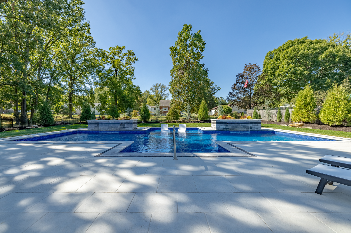 Outdoor pool with blue water, fountain, and surrounding trees in a sunny park