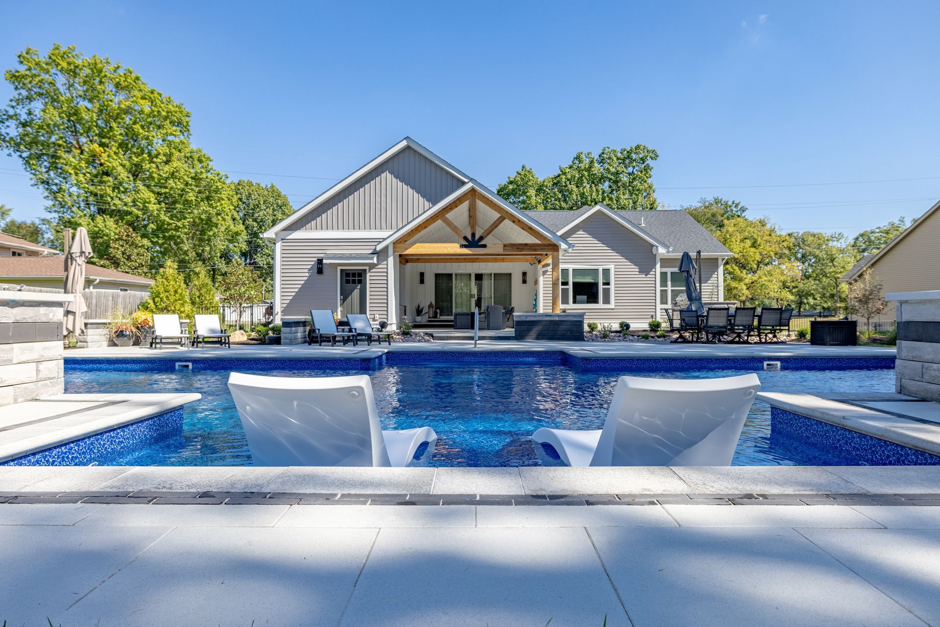 Modern house with a blue-tiled backyard pool and water features under a clear sky