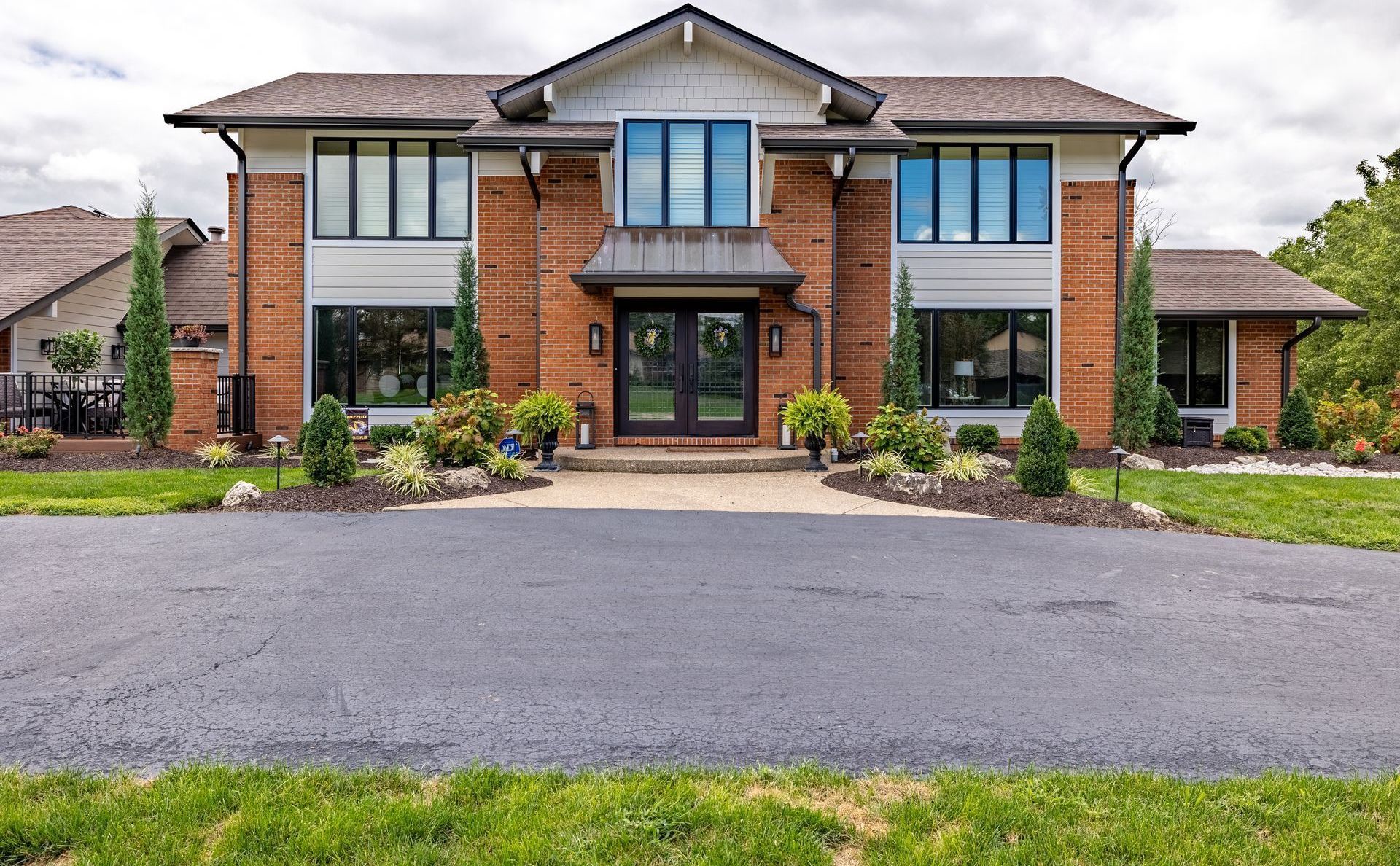 Large modern two-story brick house with a wide driveway and landscaped front yard