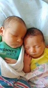 two newborn babies are sleeping next to each other in a hospital bed .