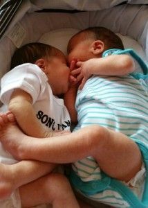 two babies are sleeping next to each other in a crib .