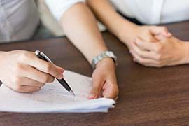 a person is writing on a piece of paper with a pen .