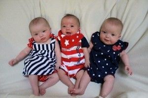three babies are sitting next to each other on a bed .