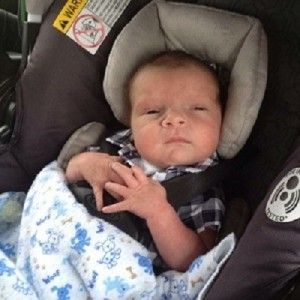 a baby is sitting in a car seat with a warning sign on it .
