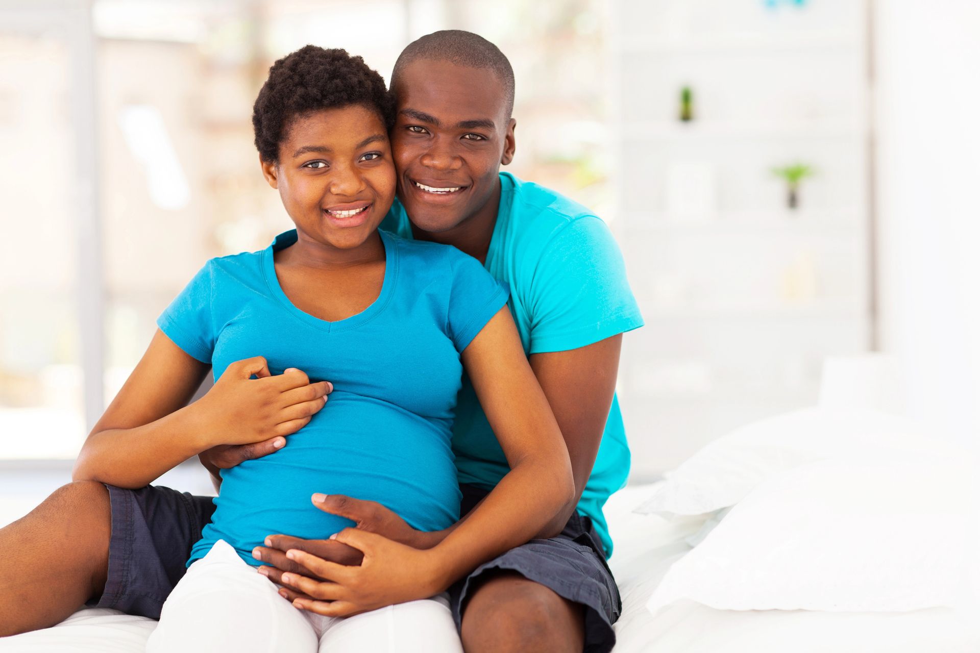 couple in blue holding each other and expecting a baby