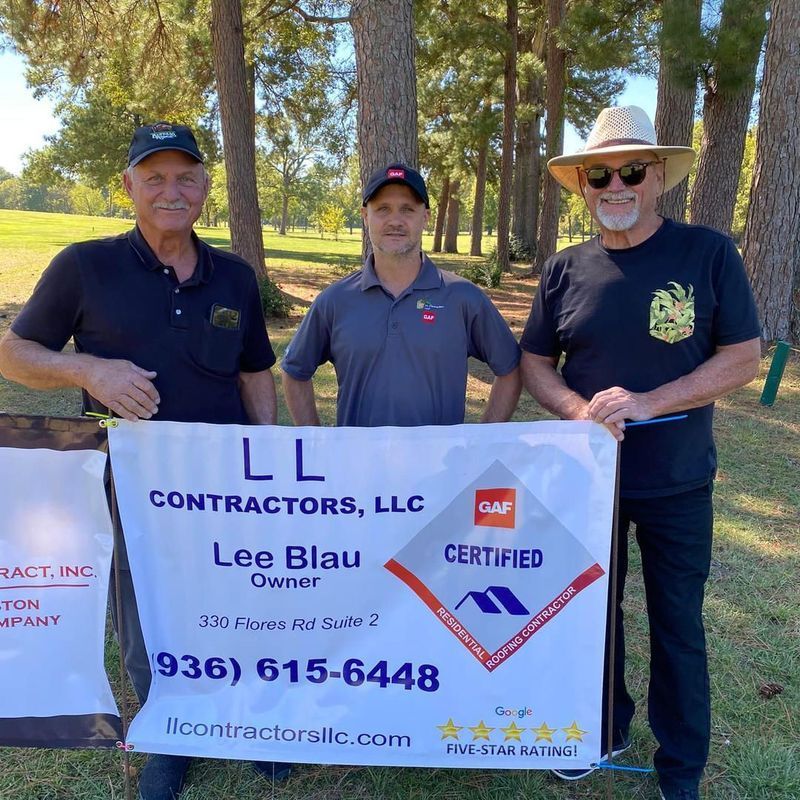 Three men holding a banner for LL Contractors on a golf course; one in a hat.