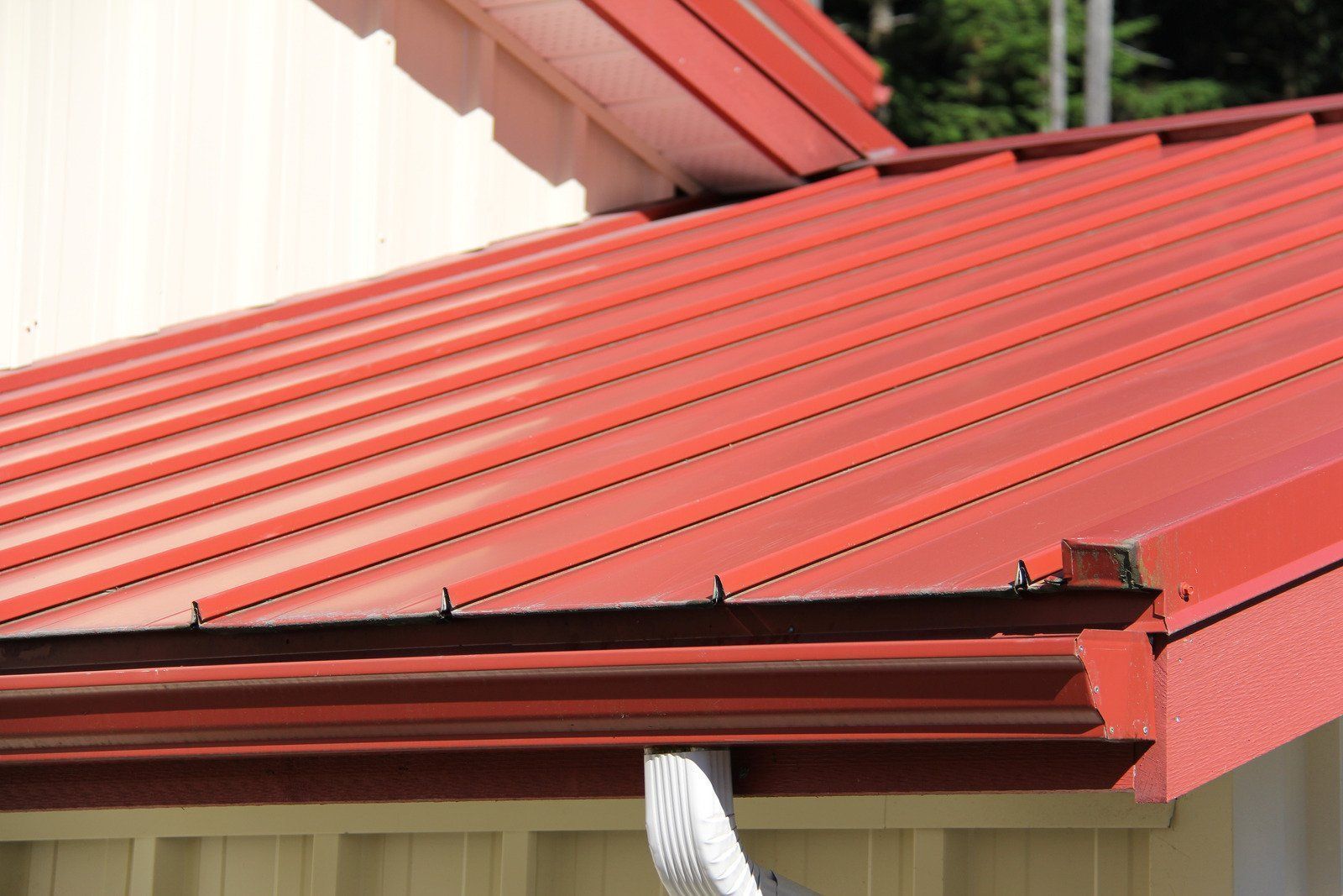 Red metal roof with matching gutters and a white building exterior.