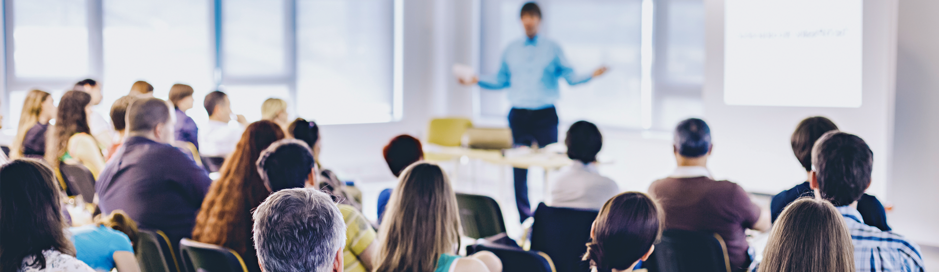 Présentation en classe avec un orateur s'adressant à un public assis en rangs.