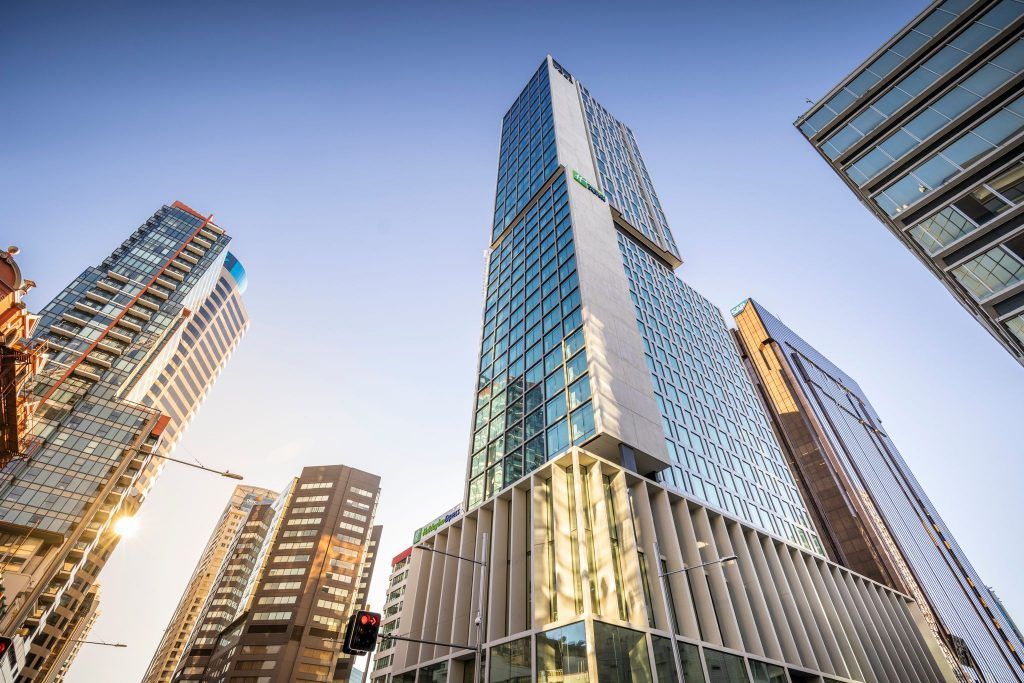 Modern glass skyscrapers viewed from below against a clear blue sky