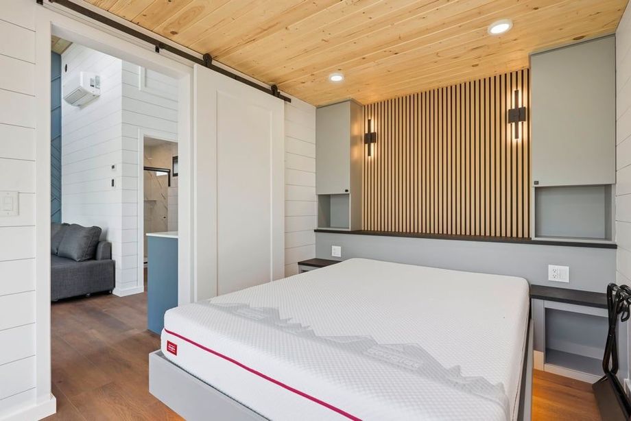 Modern bedroom with white bed, wood slat accent wall, and large sliding closet doors