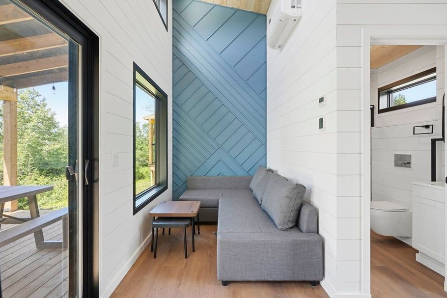 Modern tiny living room with gray sofa, blue accent wall, and view of outdoor patio