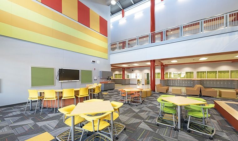 Bright modern cafeteria with colorful tables, chairs, and a high ceiling.