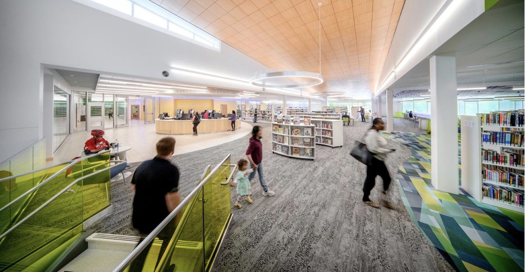 Modern library interior with people walking between bookshelves and study areas