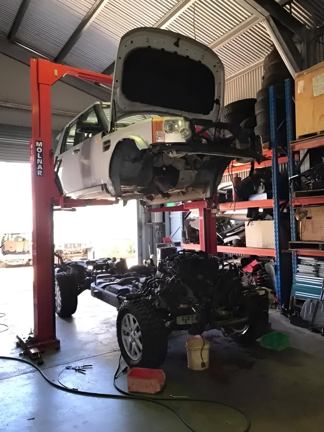 A Car is Being Lifted on a Lift in a Garage — Land Rover Spares In Mackay, QLD