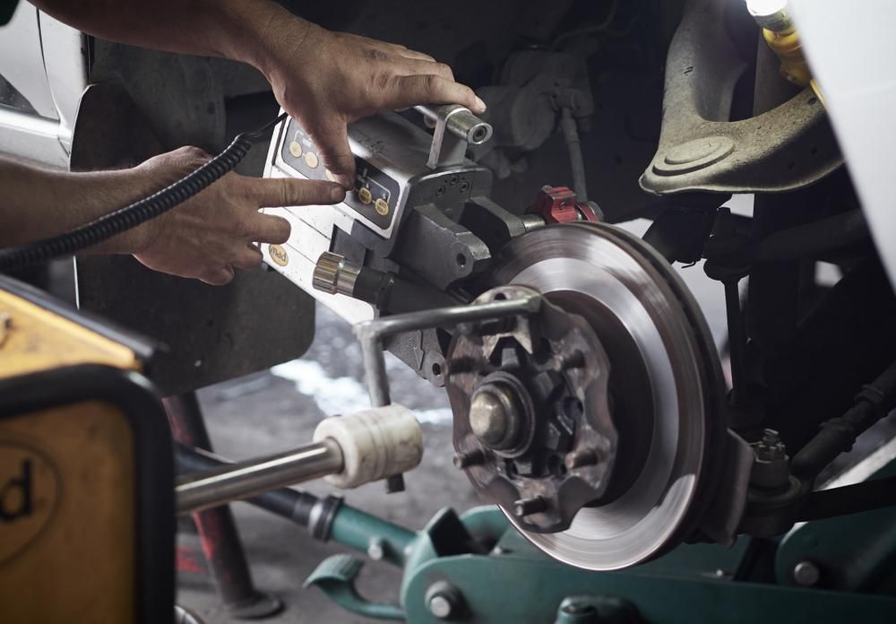 A Man is Working on a Brake Disc on a Car — Land Rover Spares In Mackay, QLD